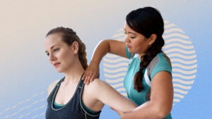 A physical therapist holds a patient's arm and palpates their shoulder in front of an abstract blue background